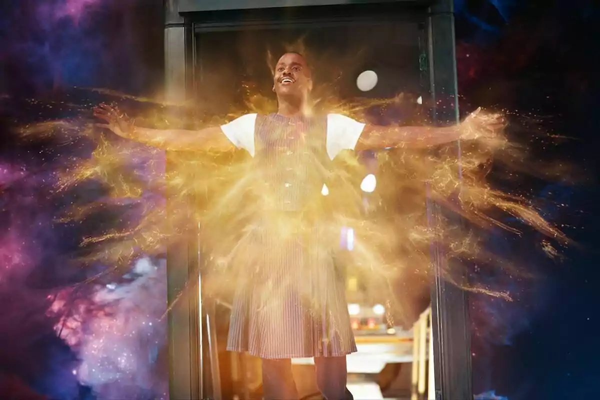 Ncuti Gatwa dret amb els braços estesos envoltat d’una resplendor daurada i un fons còsmic acolorit a Doctor Who Ncuti Gatwa dret amb els braços estesos envoltat d’una resplendor daurada i un fons còsmic acolorit a Doctor Who