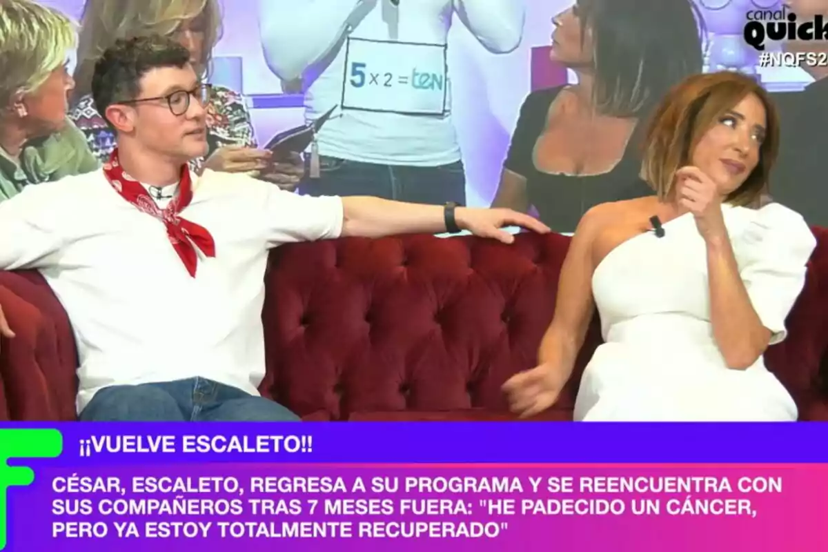 María Patiño i Escaleto estan asseguts en un sofà vermell durant Ni que fuéramos, amb un text a la part inferior que anuncia el retorn d'una persona al programa després de recuperar-se d'una malaltia. María Patiño i Escaleto estan asseguts en un sofà vermell durant Ni que fuéramos, amb un text a la part inferior que anuncia el retorn d'una persona al programa després de recuperar-se d'una malaltia.
