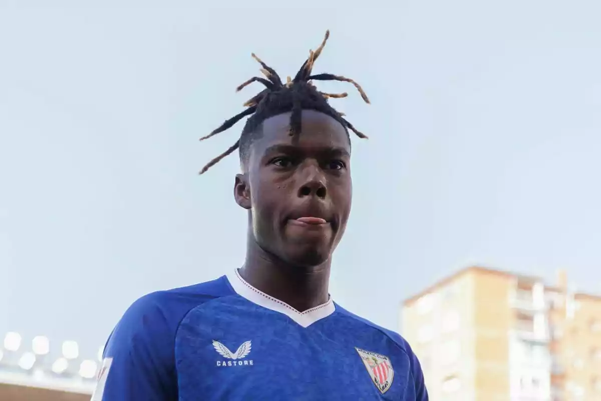 Nico Williams con camiseta azul y el logo de Castore, con el cabello recogido en rastas, saca la lengua mientras mira hacia adelante. Nico Williams con camiseta azul y el logo de Castore, con el cabello recogido en rastas, saca la lengua mientras mira hacia adelante.