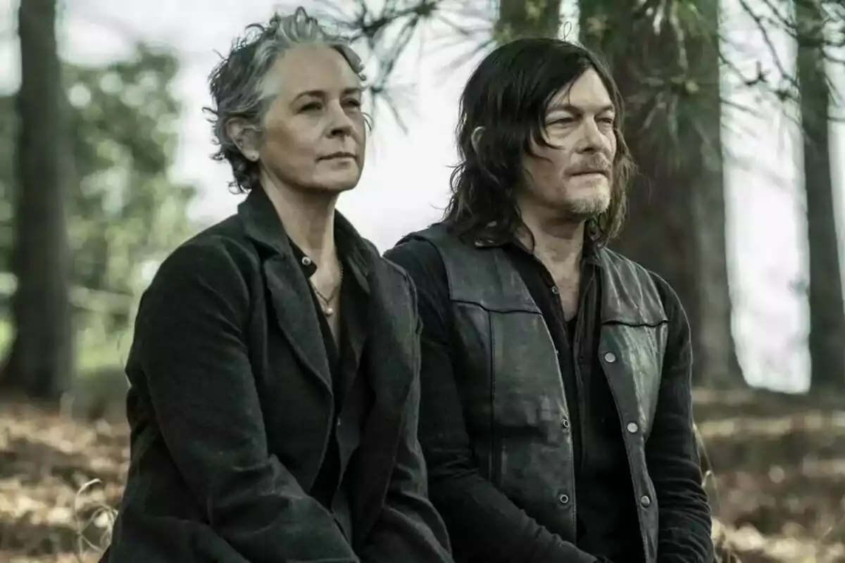 Fotografía de Norman Reedus y Melissa McBride sentadas en un bosque, una mujer de cabello corto y canoso y un hombre de cabello largo y oscuro en The Walking Dead: Daryl Dixon