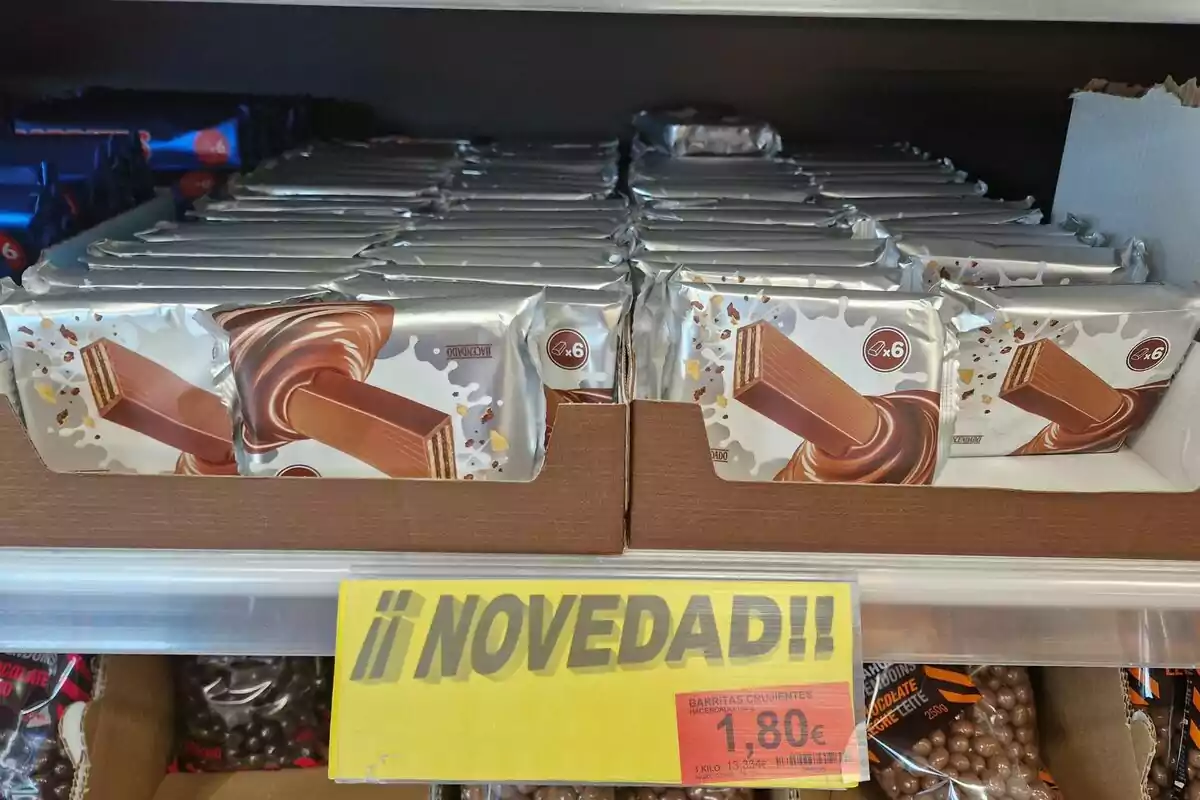 Paquete de barritas crujientes de chocolate en exhibición con un cartel amarillo que dice Paquete de barritas crujientes de chocolate en exhibición con un cartel amarillo que dice