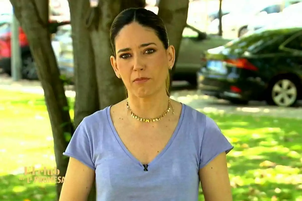 Nuria Martín de cabell fosc recollit i samarreta lila dreta a l’aire lliure amb expressió seriosa, arbres i cotxes desenfocats al fons a El Club de La Promesa Nuria Martín de cabell fosc recollit i samarreta lila dreta a l’aire lliure amb expressió seriosa, arbres i cotxes desenfocats al fons a El Club de La Promesa