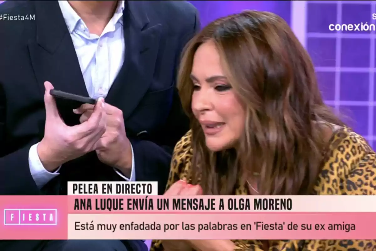 Olga Moreno amb expressió seriosa apareix en un programa de televisió mentre un home sosté un telèfon mòbil. Olga Moreno amb expressió seriosa apareix en un programa de televisió mentre un home sosté un telèfon mòbil.