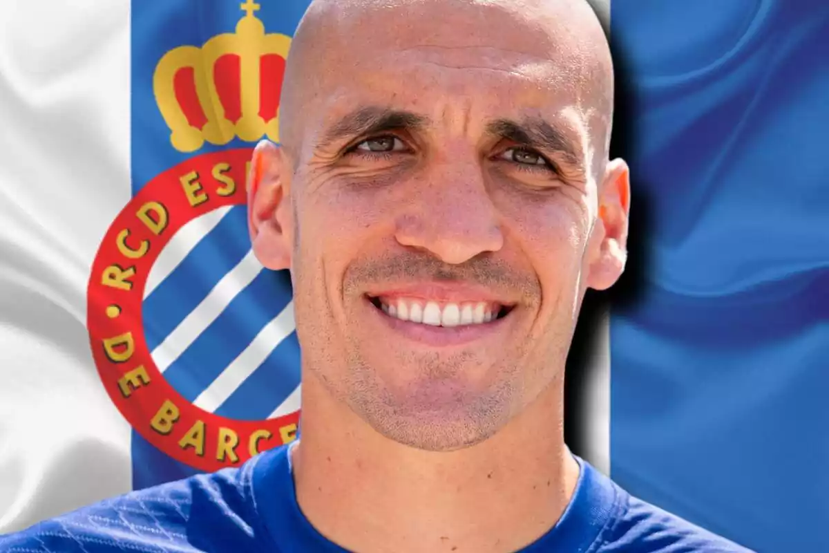 Oriol Romeu amb un gran somriure davant un escut del RCD Espanyol