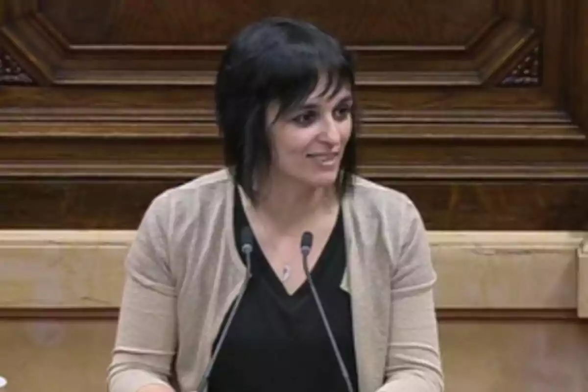 Sílvia Orriols parlant al faristol del Parlament amb micròfons en un entorn de fusta.