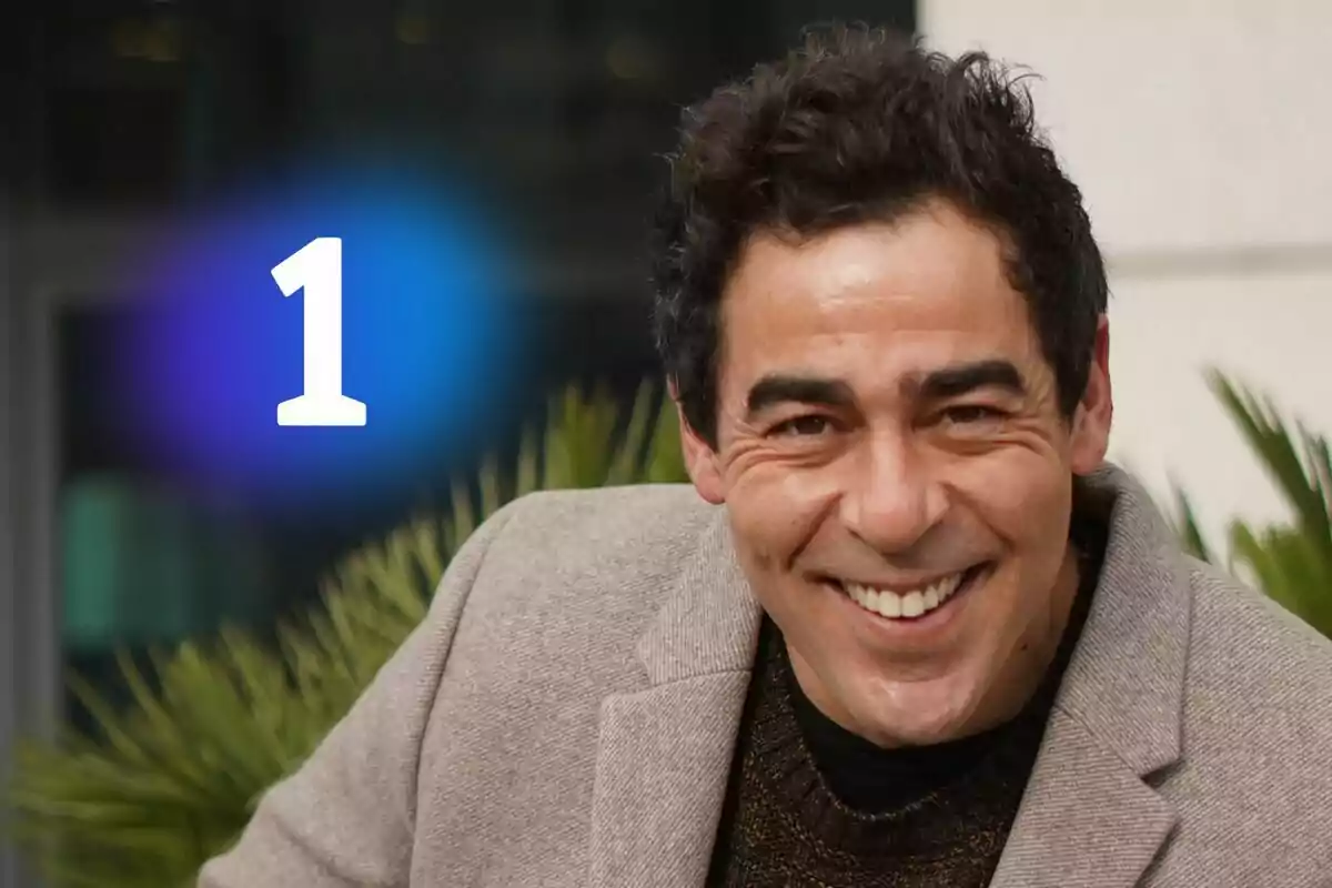 Pablo Chiapella somrient amb cabell fosc i jaqueta beix, el logotip de La 1 gran en color blanc sobre una resplendor blava