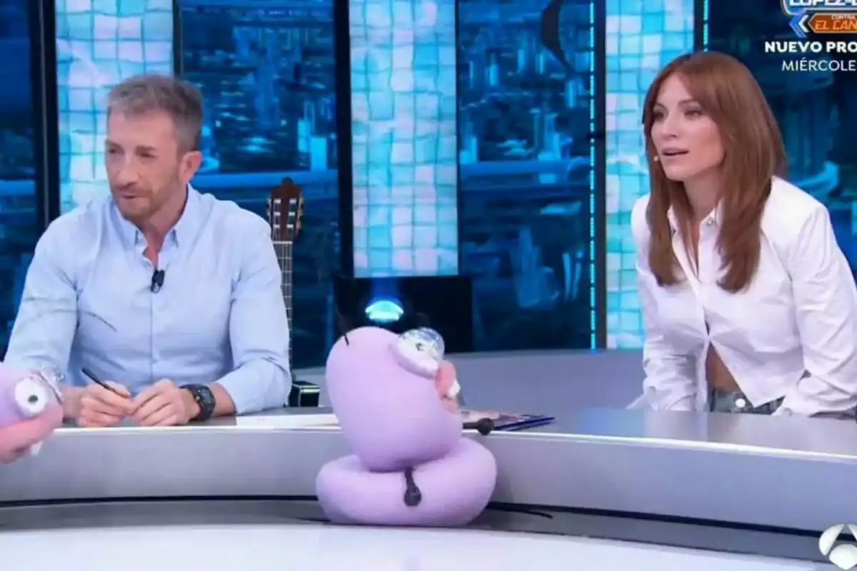 Pablo Motos al costat d'Edurne assegudes al plató del Hormiguero amb marionetes morades sobre la taula.