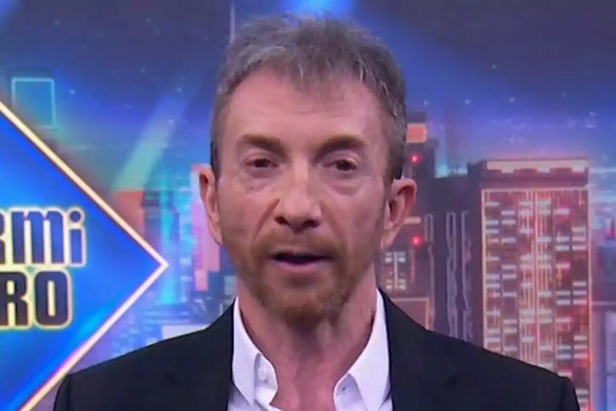 Pablo Motos amb barba i cabell curt apareix en un programa de televisió amb un fons colorit i urbà a El Hormiguero.