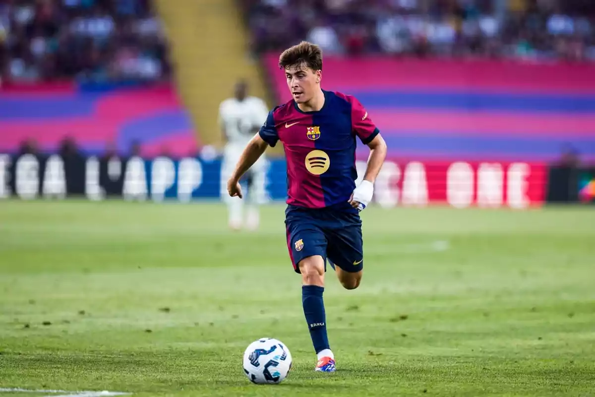 A FC Barcelona football player running with the ball on a football field during a match.