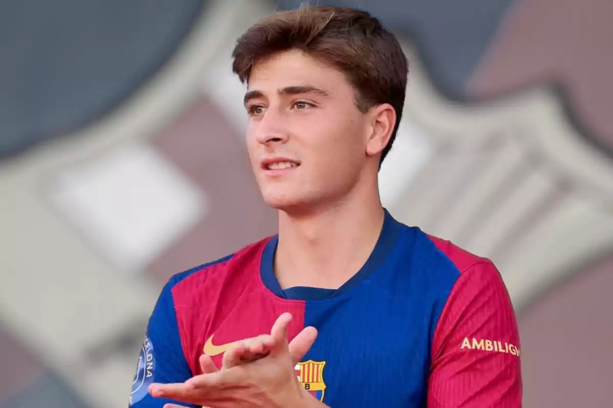 A young man in a blue and red soccer jersey clapping.