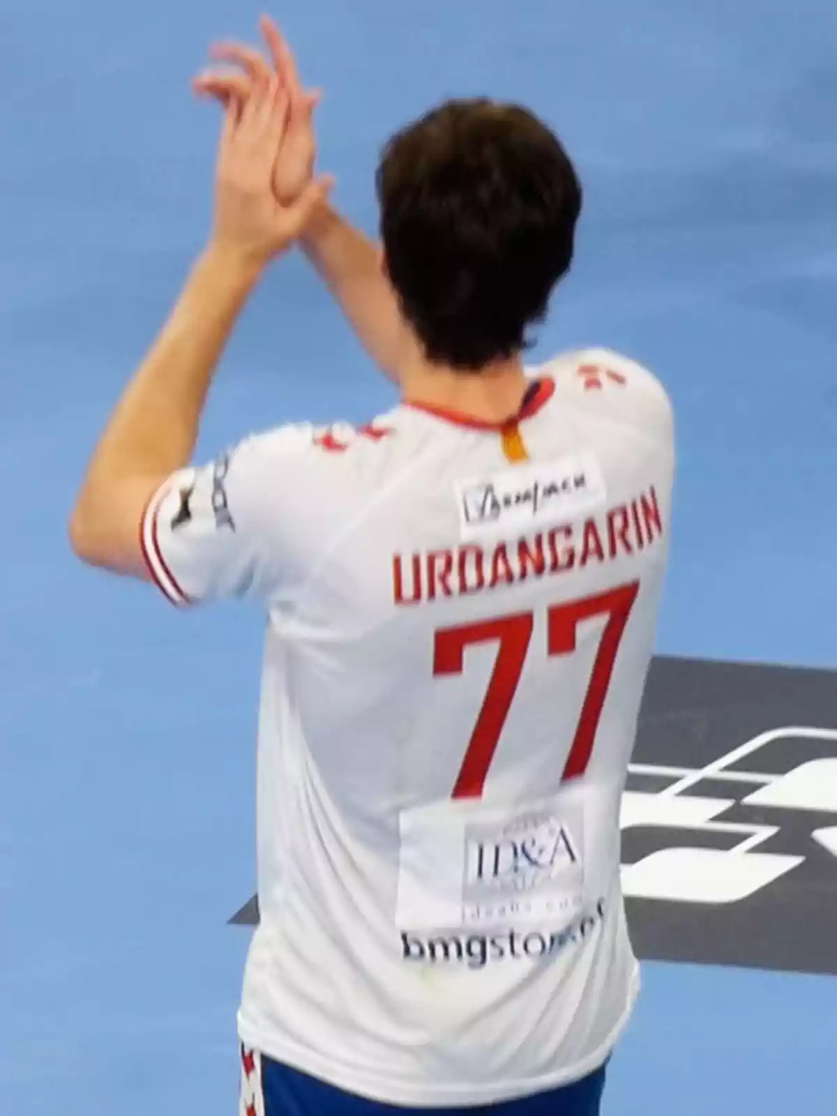 Pablo Urdangarin con camiseta blanca y el número 77 aplaudiendo en una cancha. Pablo Urdangarin con camiseta blanca y el número 77 aplaudiendo en una cancha.