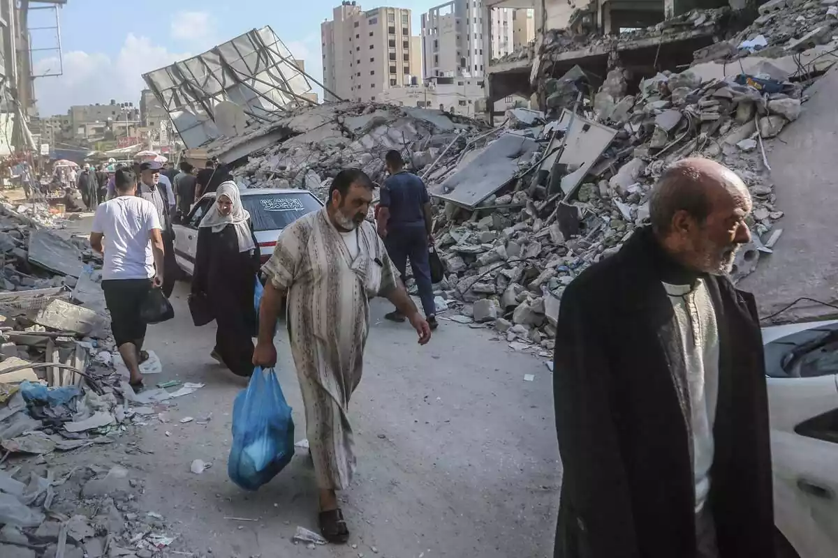 Els palestins passen al costat de les restes dels edificis destruïts pels atacs aeris israelians a Khan Yunis. Centenars de milers de palestins fugen al sud de la Franja de Gaza per evitar una esperada invasió terrestre israeliana, els subministraments essencials s'estan esgotant