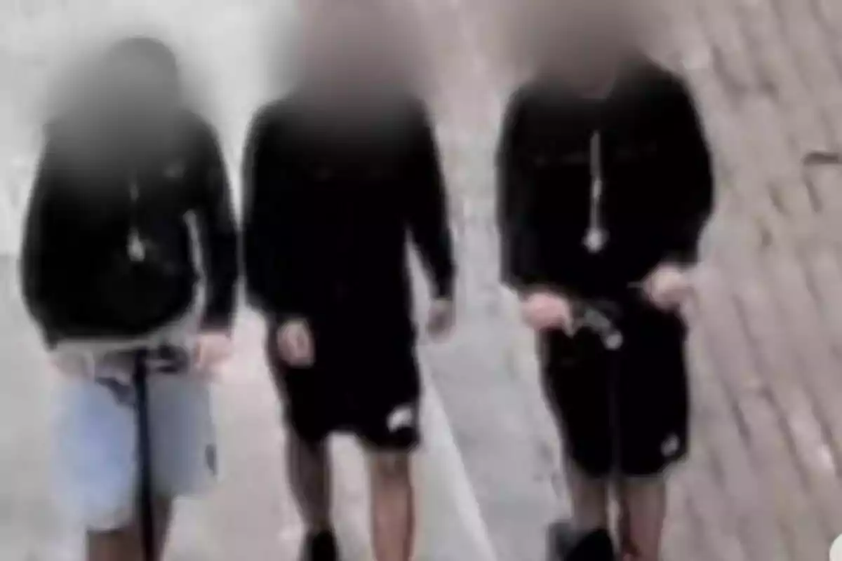 Tres persones caminant per un carrer amb els seus rostres desenfocats.