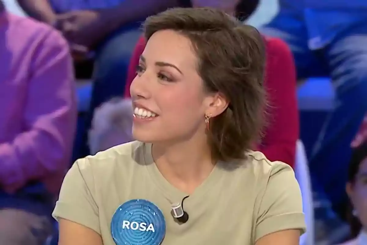Rosa amb una samarreta clara somriu mentre participa en un programa de televisió, porta una insígnia blava amb el nom Rosa. Captura de 'Pasapalabra'. Rosa amb una samarreta clara somriu mentre participa en un programa de televisió, porta una insígnia blava amb el nom Rosa. Captura de 'Pasapalabra'.
