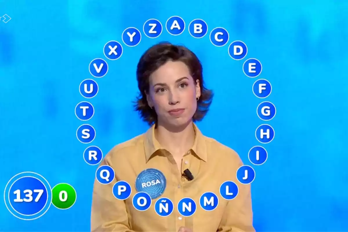 Rosa competing on a TV show with alphabet letters in a circle around her and a scoreboard showing the number 137. Screenshot from 'Pasapalabra' Rosa competing on a TV show with alphabet letters in a circle around her and a scoreboard showing the number 137. Screenshot from 'Pasapalabra'