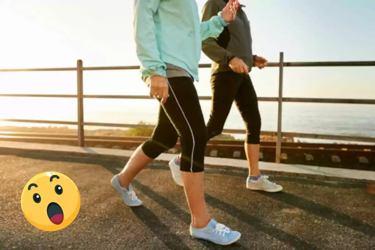 Two people walking outside next to a barrier with a surprised emoji in the lower left corner.