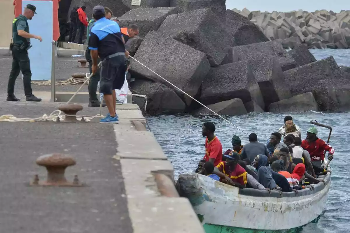 Uns guàrdies civils, des del port de Hierro (Canàries) arrosseguen amb una corda una pastera plena d'immigrants subsaharians
