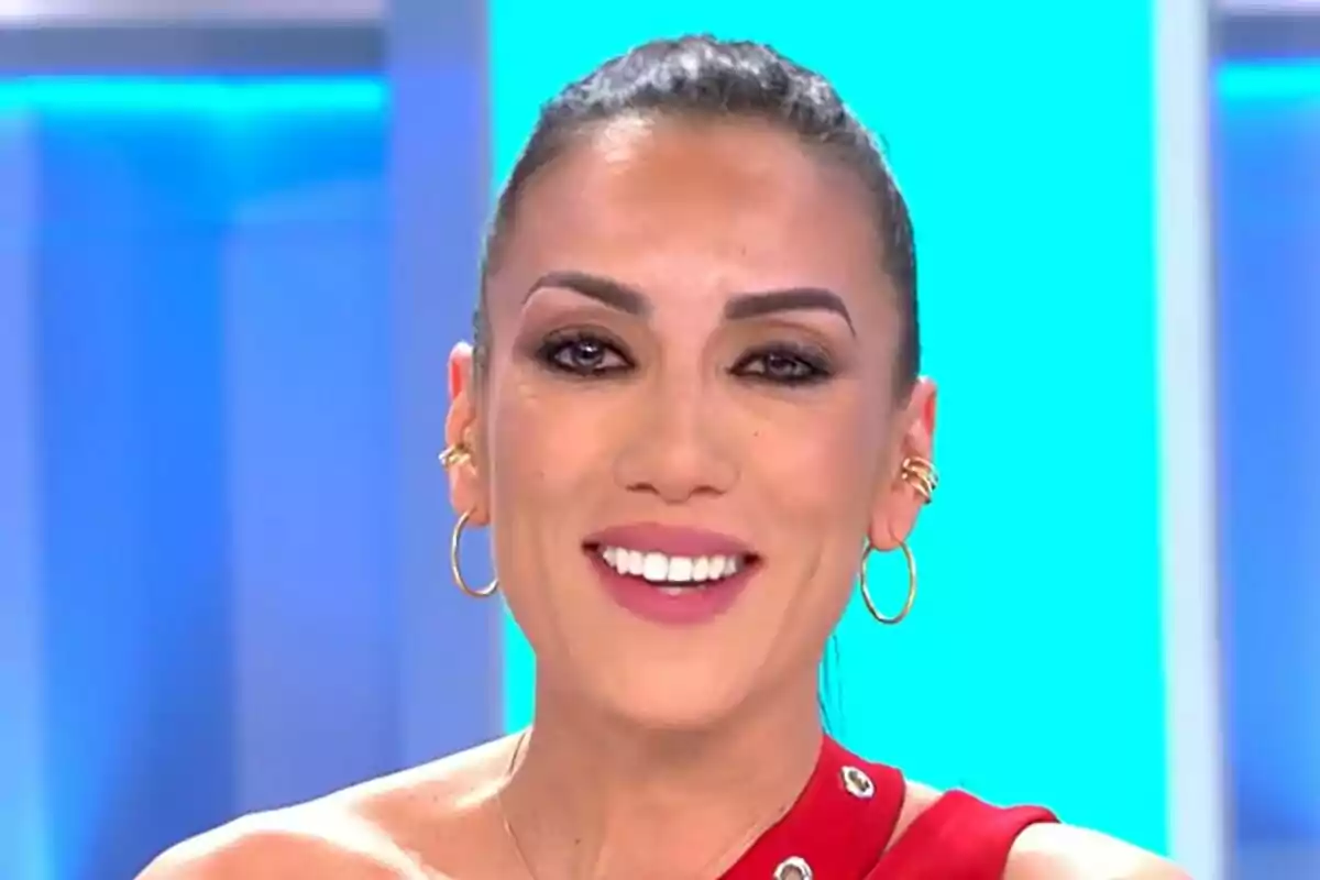 Patricia Pardo sonriendo emocionada con un vestido rojo y fondo azul en Vamos a ver.