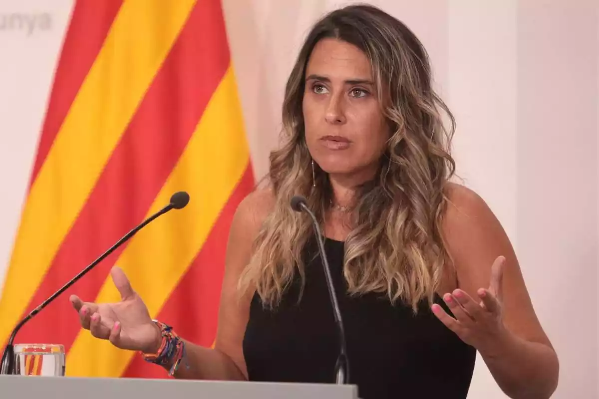 Pla mitjà de Patrícia Plaja amb una samarreta sense mànigues negra i obrint els braços a la sala de premsa del Palau de la Generalitat
