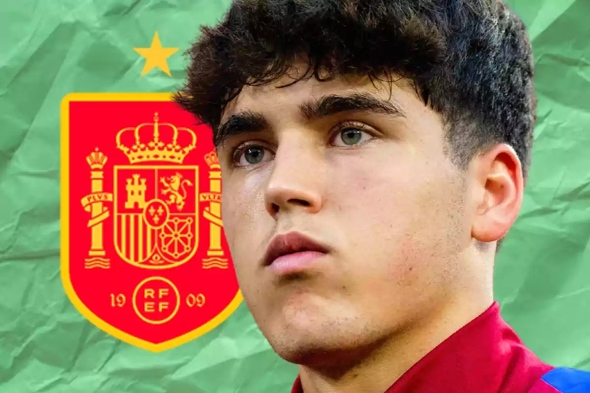 Un joven con una camiseta roja frente al escudo de la selección de fútbol de España.