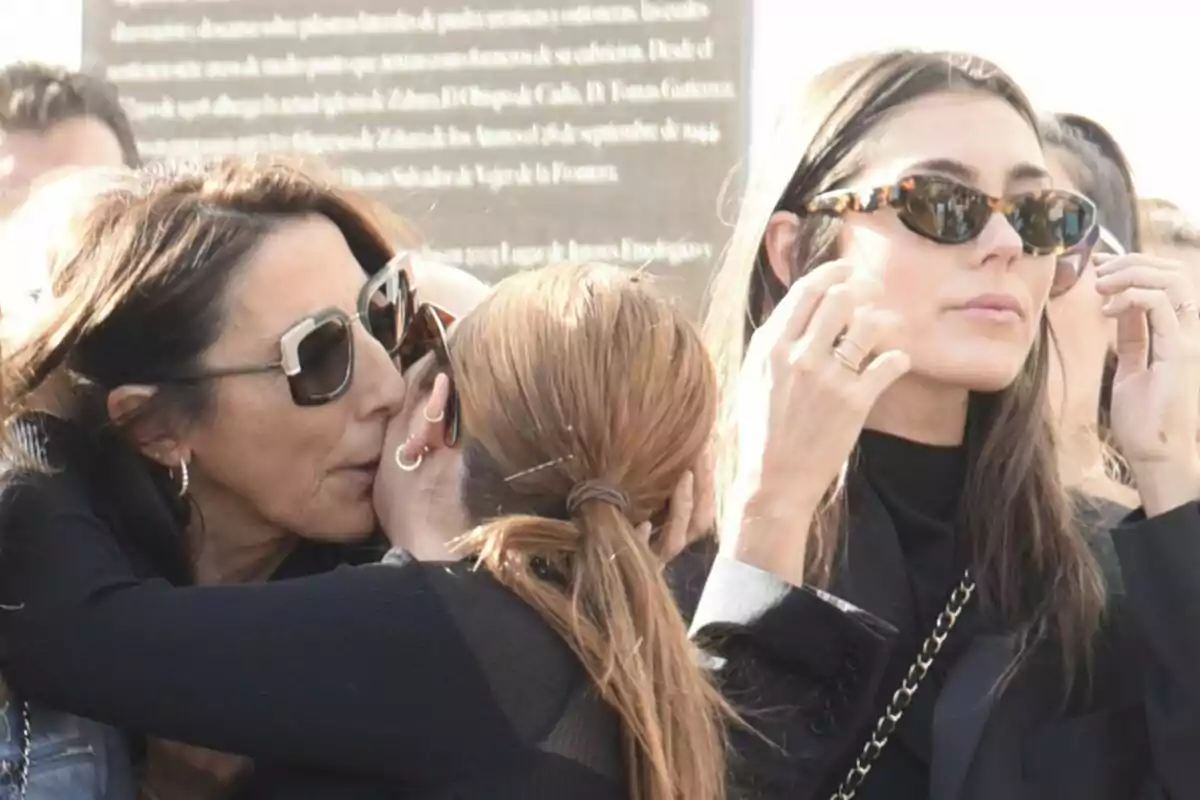 Paz Padilla i Anna Ferrer Padilla amb ulleres de sol interactua en un ambient exterior a un funeral.