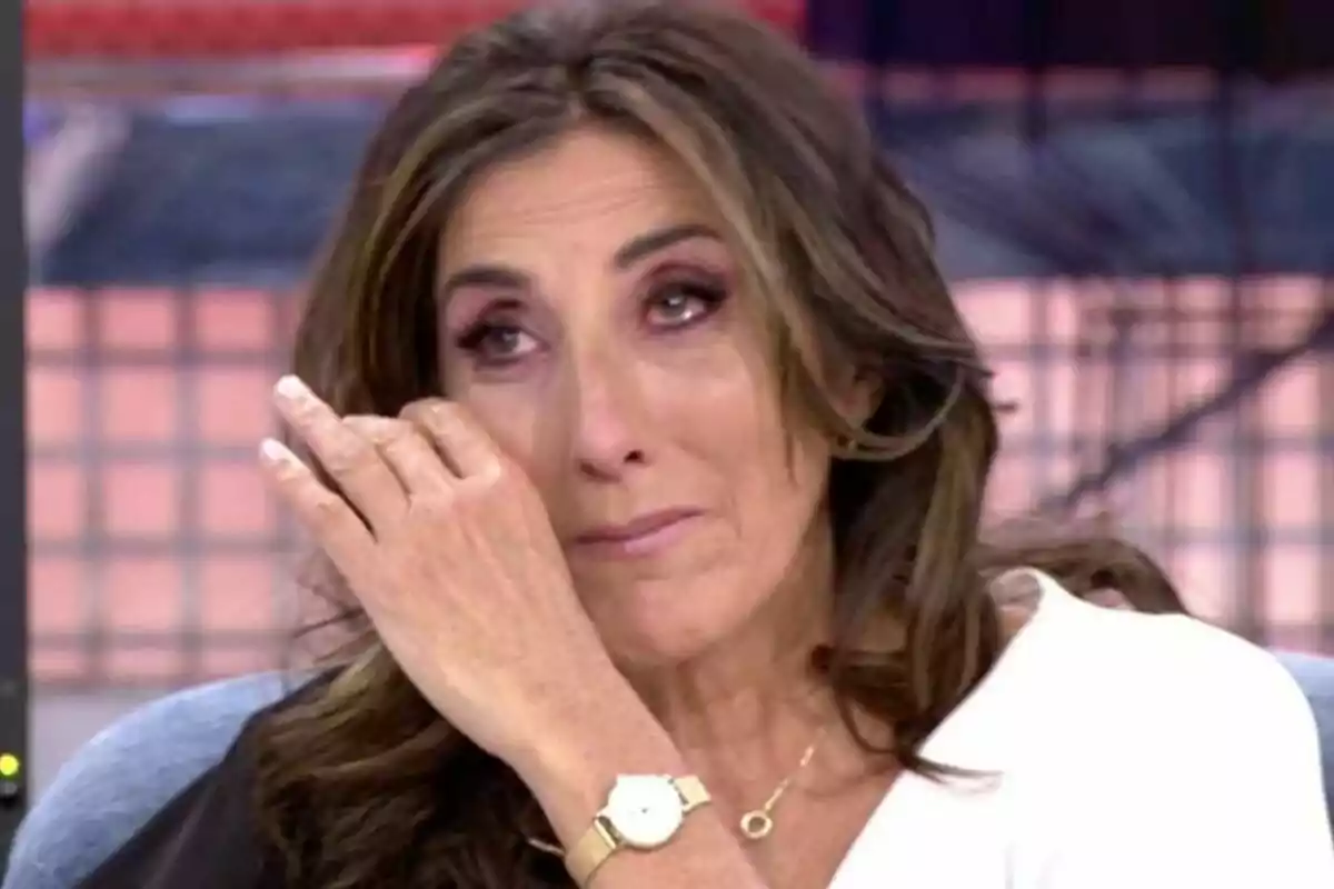 Pau Padilla amb expressió emocional s'asseca una llàgrima mentre està asseguda en un entorn d'estudi de televisió.