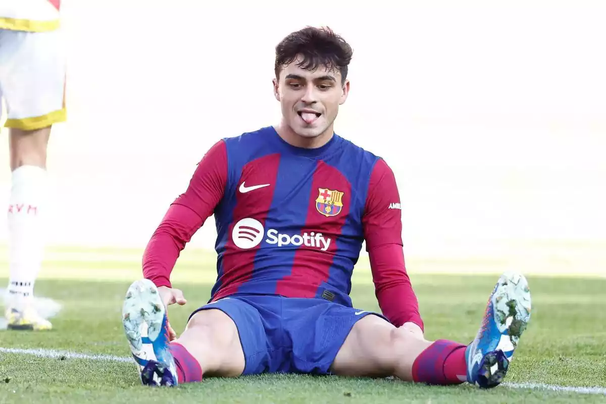 Pedri assegut a terra amb la llengua a fora mirant-se la bota dreta durant un partit del FC Barcelona