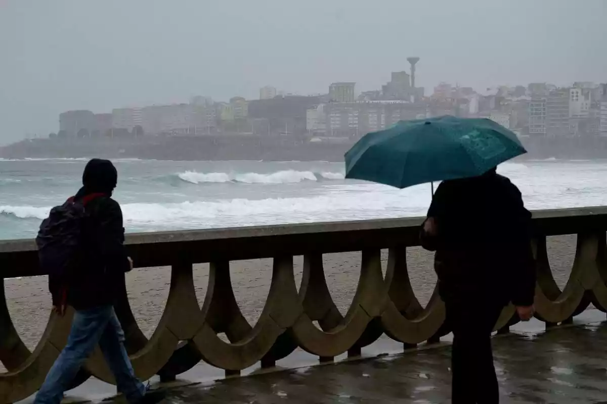 Dues persones caminant per un passeig marítim a Galícia