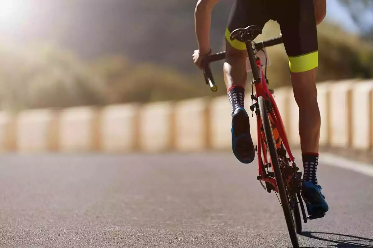 Plànol curt de les cames d´un ciclista conduint una bicicleta per una carretera