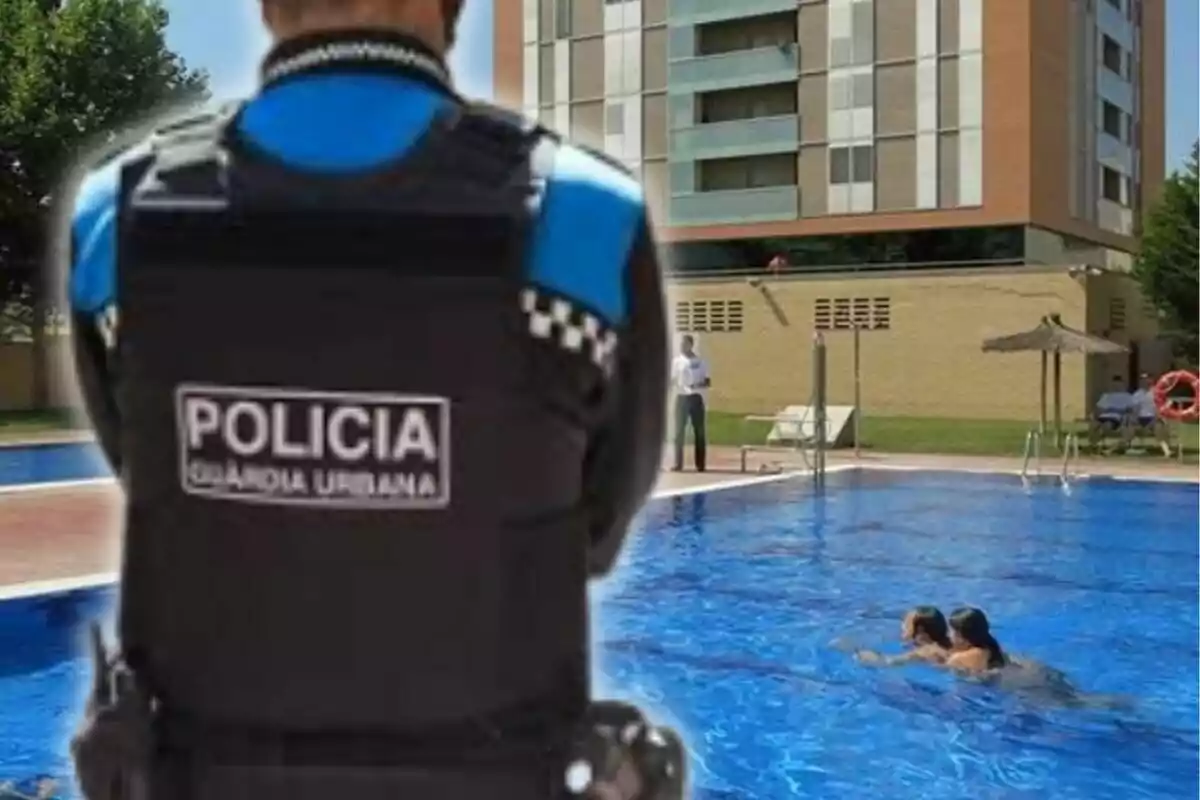 Un policia de la Guàrdia Urbana observa una piscina on neden dues persones, amb un edifici d'apartaments al fons.