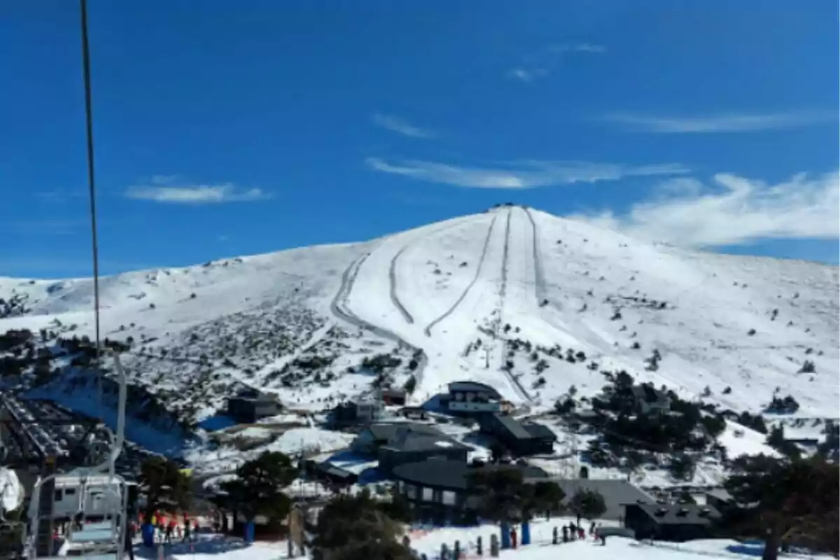 Vista de una montaña nevada con pistas de esquí y un cielo azul claro.