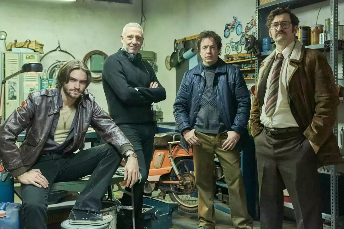 Raúl Arévalo, Vito Sanz, Agustín Otón i un altre home posen en un taller mecànic envoltats d'eines i una motocicleta durant el rodatge de Per Cent Milions.