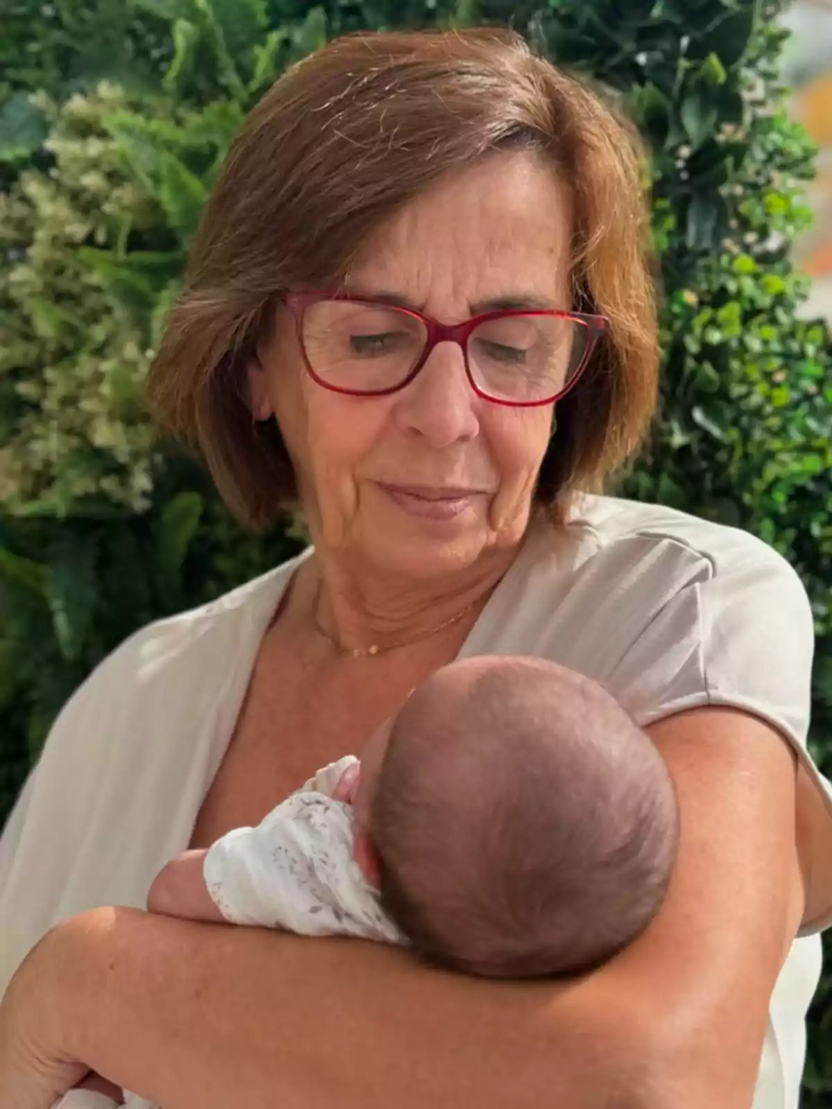 Mercedes Bernal sosté en braços l'Alma mentre la mira amb tendresa envoltada de plantes verdes. Mercedes Bernal sosté en braços l'Alma mentre la mira amb tendresa envoltada de plantes verdes.