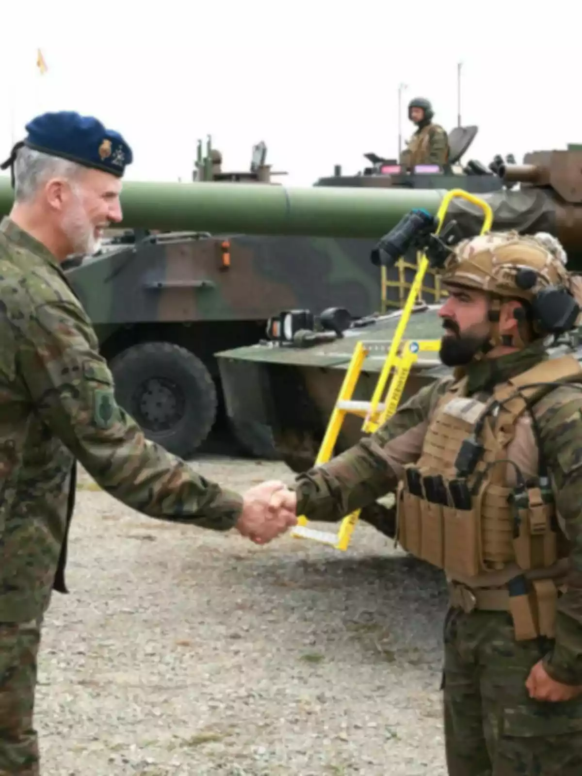 Felip VI i un altre home amb uniforme de camuflatge es donen la mà davant d’un vehicle blindat en un entorn a l’aire lliure. Felip VI i un altre home amb uniforme de camuflatge es donen la mà davant d’un vehicle blindat en un entorn a l’aire lliure.