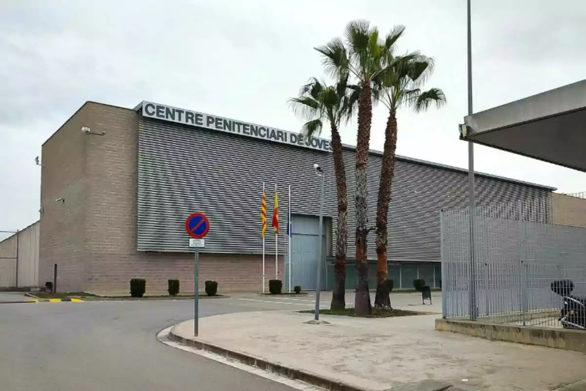 Edifici del Centre Penitenciari de Joves amb palmeres i banderes a l'entrada.