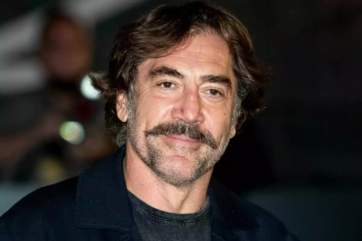 Primer plano de Javier Bardem sonriendo con un abrigo azul