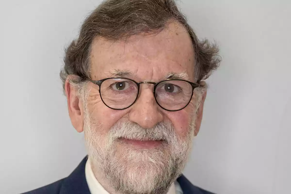 Mariano Rajoy con barba y gafas sonríe ligeramente mirando a la cámara.