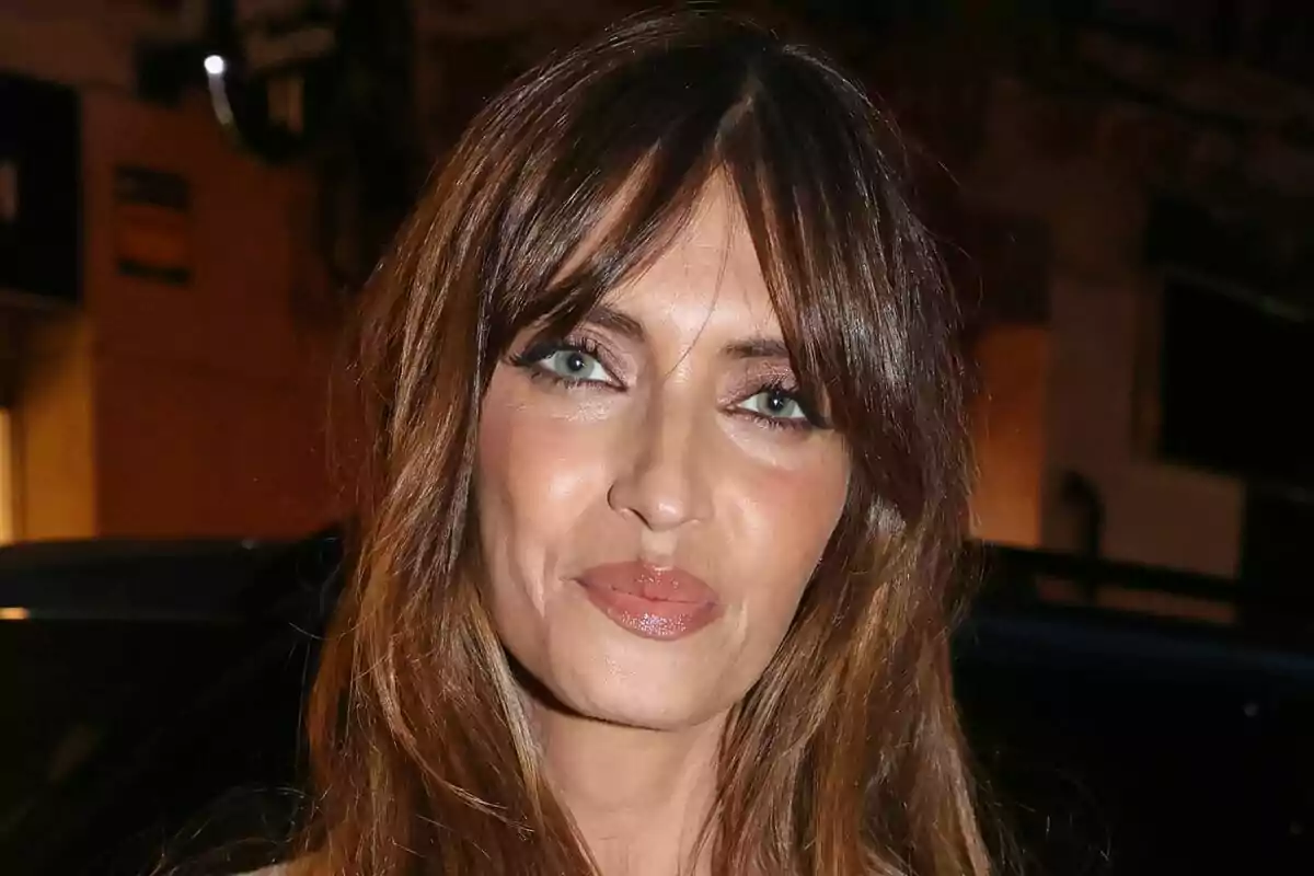 Sara Carbonero with brown hair and bangs poses for a photo in a nighttime urban setting.