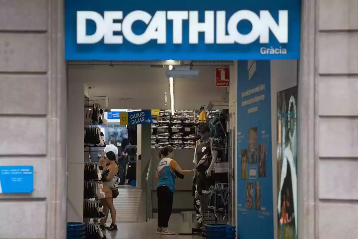 Imatge de l'exterior d'una botiga de Decathlon a Barcelona amb una dependenta col·locant productes a l'interior