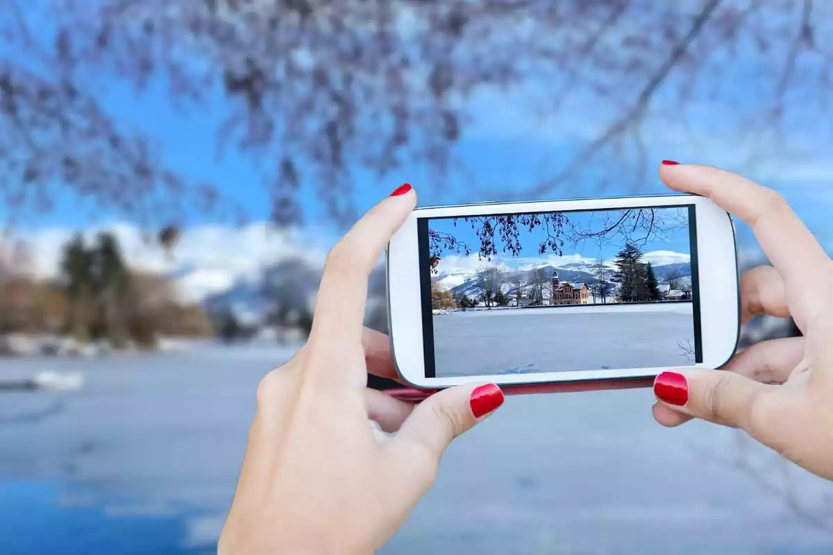 Muntatge fotogràfic d'un telèfon mòbil fent una foto al llac de Puigcerdà