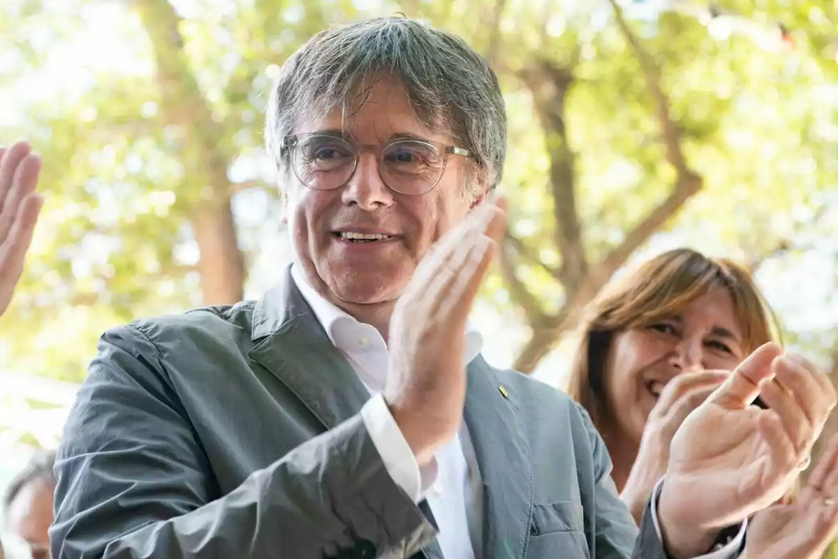 Carles Puigdemont aplaudint a l'aire lliure amb Laura Borràs somrient al fons.