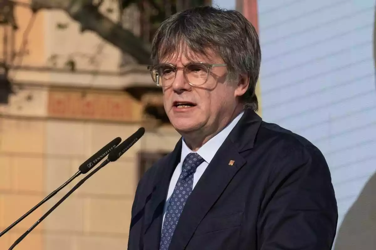 Carles Puigdemont amb vestit fosc parlant davant d'un micròfon.