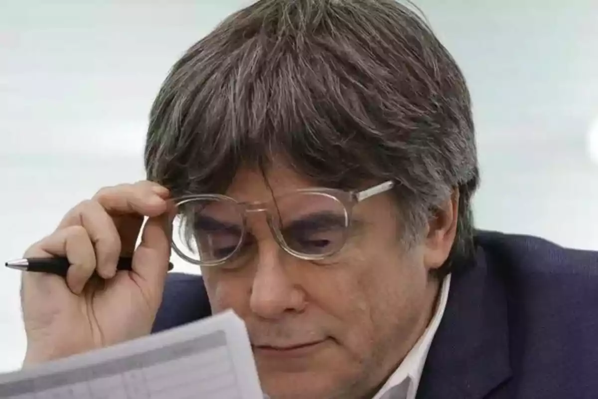 Un home amb ulleres revisa un document mentre sosté un bolígraf.
