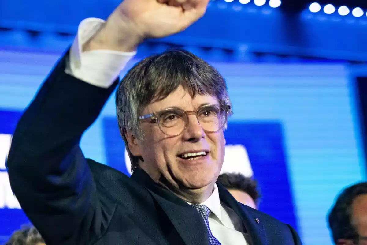 Pla mitjà de Carles Puigdemont somrient i aixecant el puny en senyal de victòria