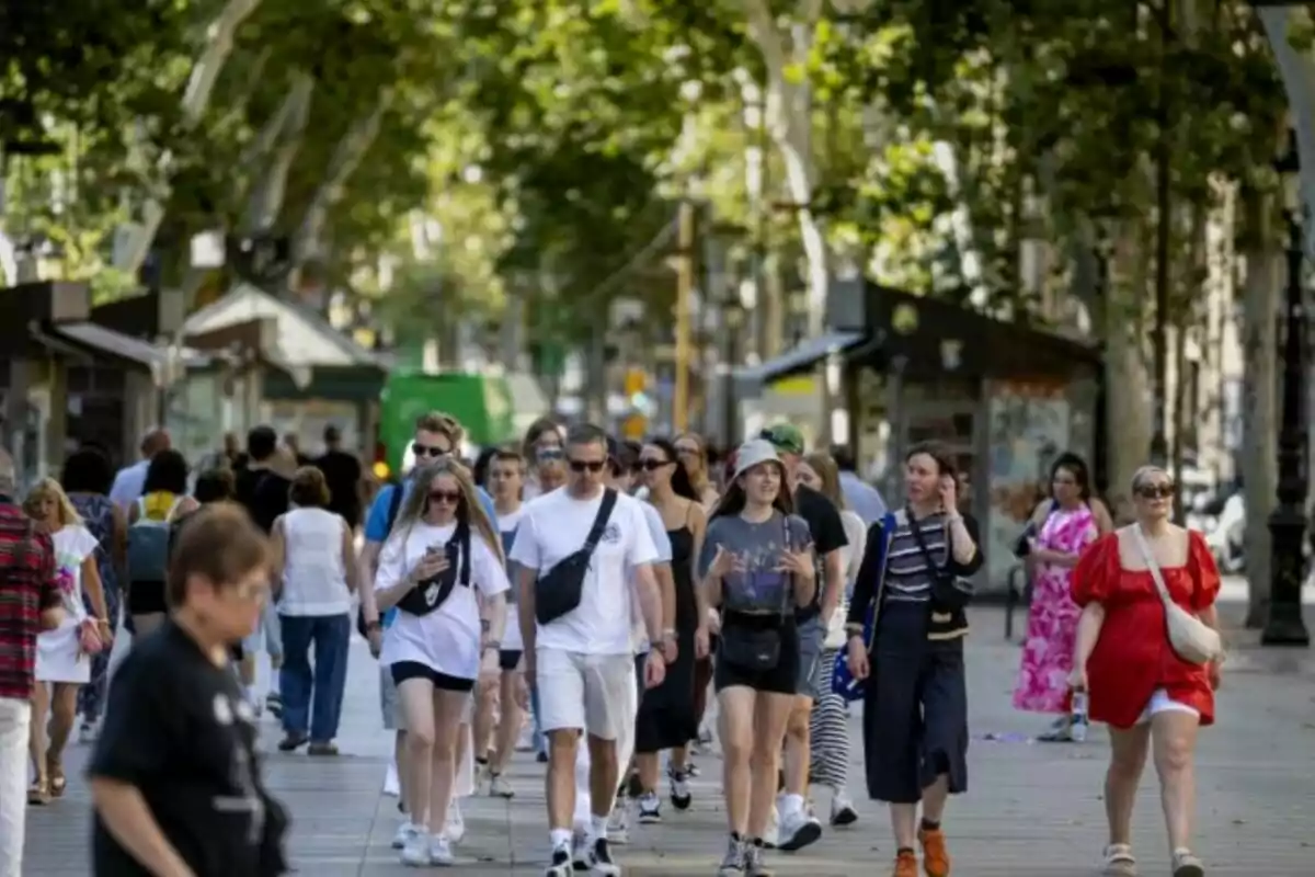 Un grup de persones caminant per la Rambla de Barcelona un dia assolellat.