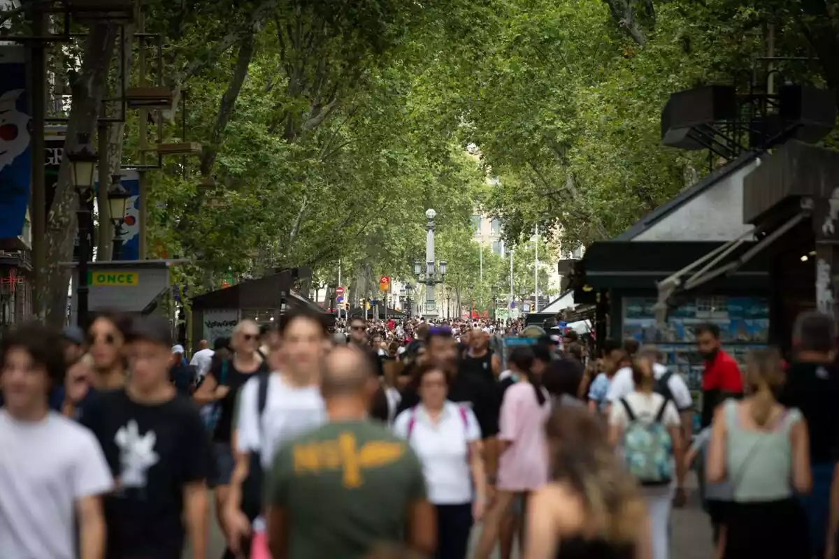 Imatge de desenes de persones caminant per la rambla de Barcelona un dia de calor