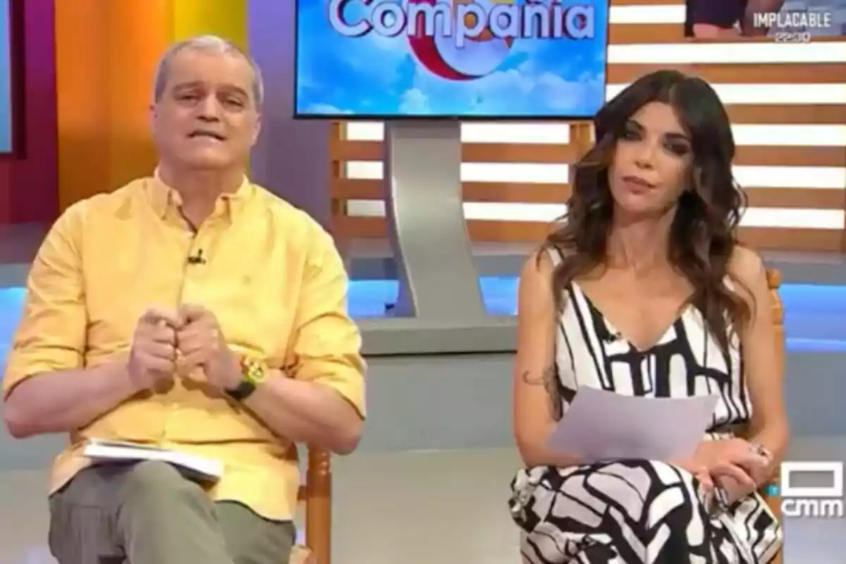 Ramón García i Gloria Santoro asseguts en un plató de televisió colorit amb un monitor al fons que mostra el nom del programa, 'En companyia'. Ramón García i Gloria Santoro asseguts en un plató de televisió colorit amb un monitor al fons que mostra el nom del programa, 'En companyia'.