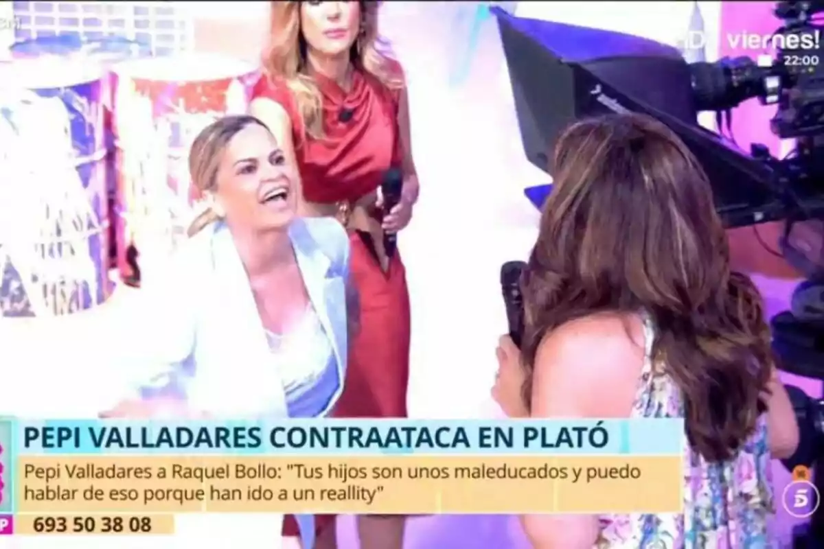 En un plató de televisió de Tardear, Pepi Valladares i Raquel Bollo estan interactuant de manera intensa mentre una càmera grava l'escena. En un plató de televisió de Tardear, Pepi Valladares i Raquel Bollo estan interactuant de manera intensa mentre una càmera grava l'escena.