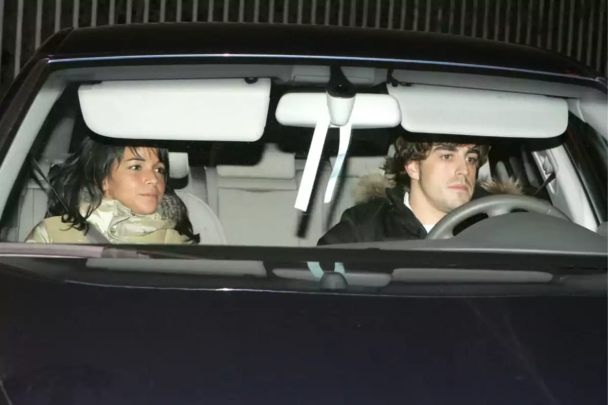 Raquel del Rosario and Fernando Alonso sitting in a car, the man is at the wheel and the woman in the passenger seat.