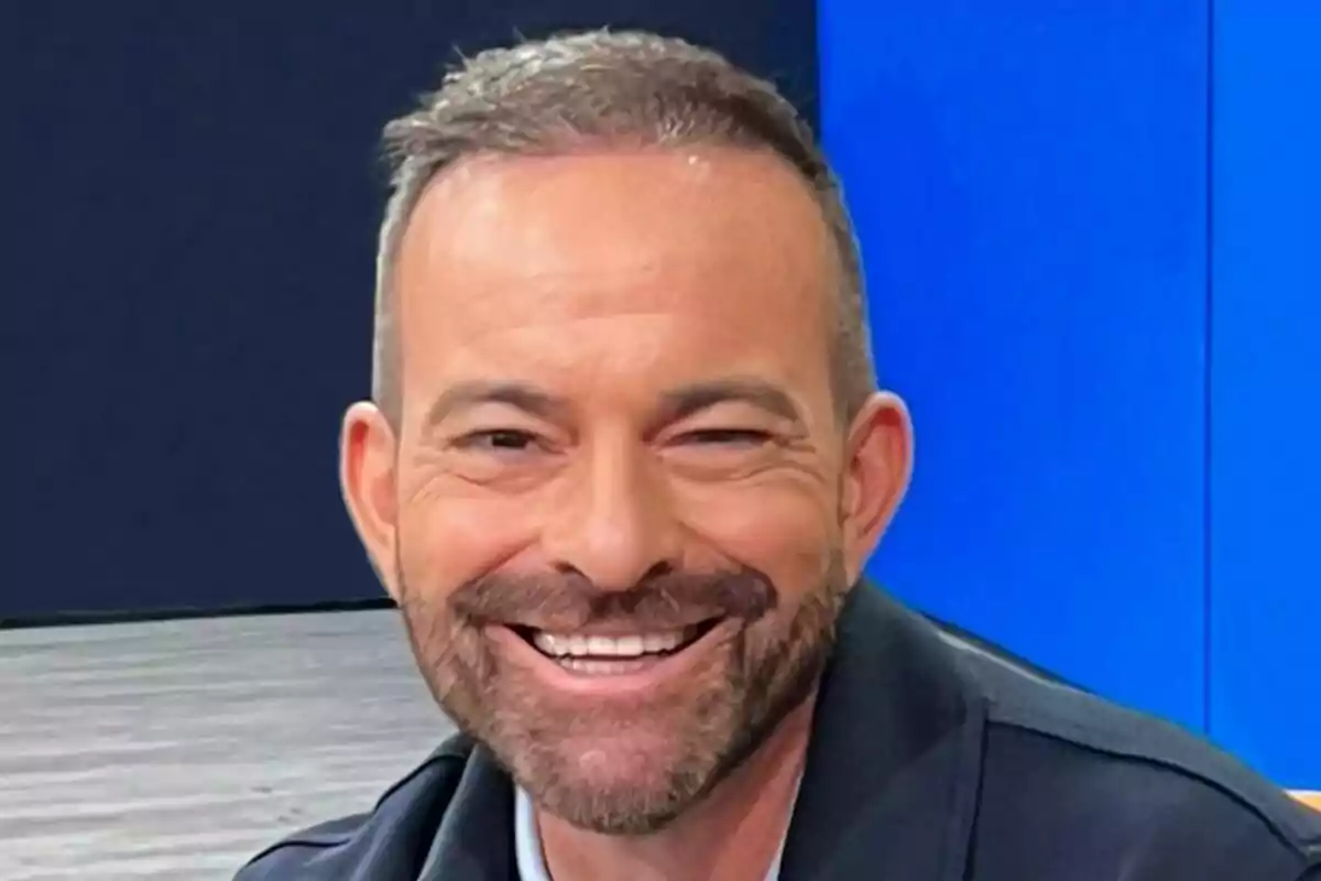 Raúl García sonriente con barba y cabello corto en un entorno con fondo azul.